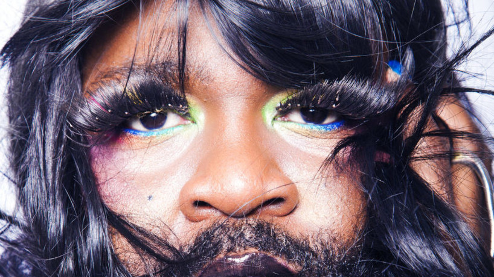 Close up portrait of artist Le Gateau Chocolat with long false eyelashes and colourful eyeshadow.