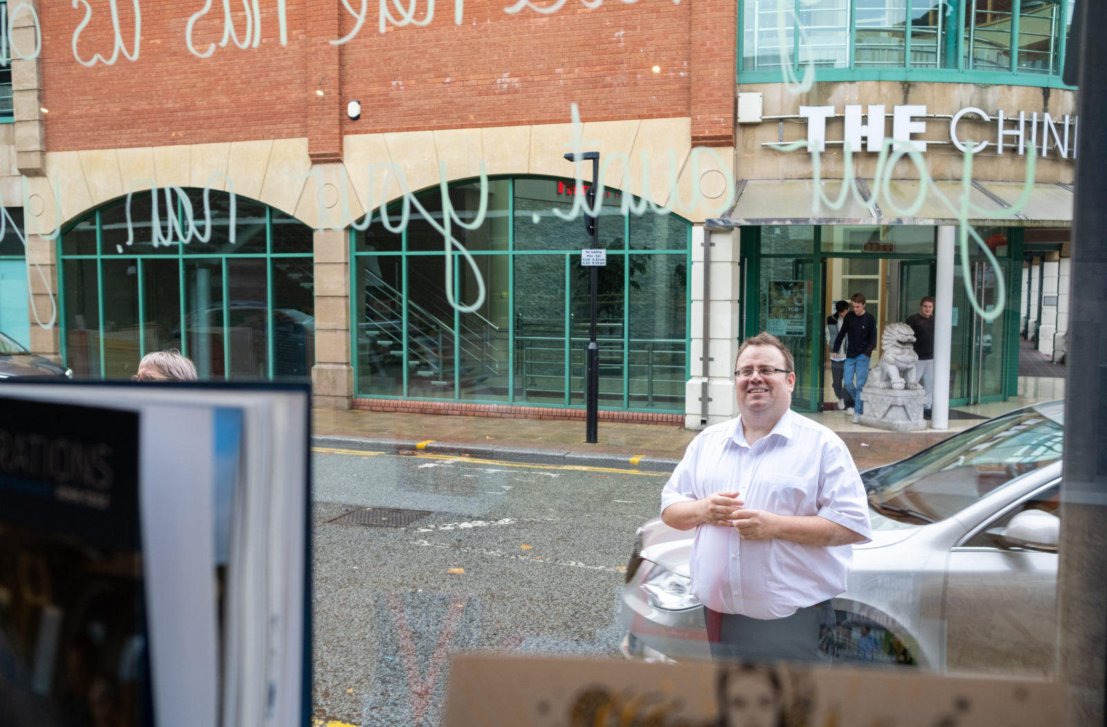 The Book Stop owner looking at the poem on the glass and smiling