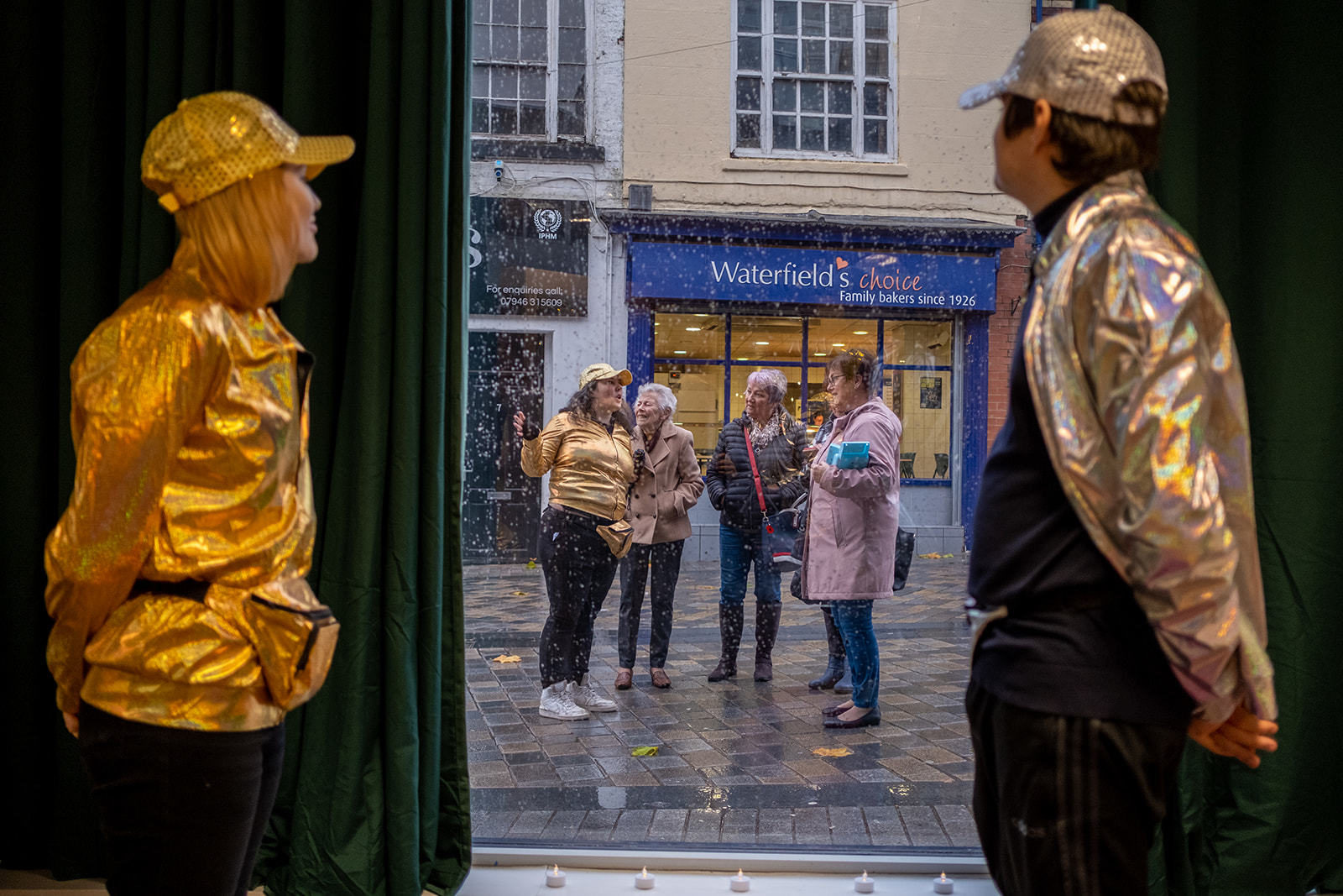 Members of the team at the window as Jenny talks about the cloakroom to people on the street