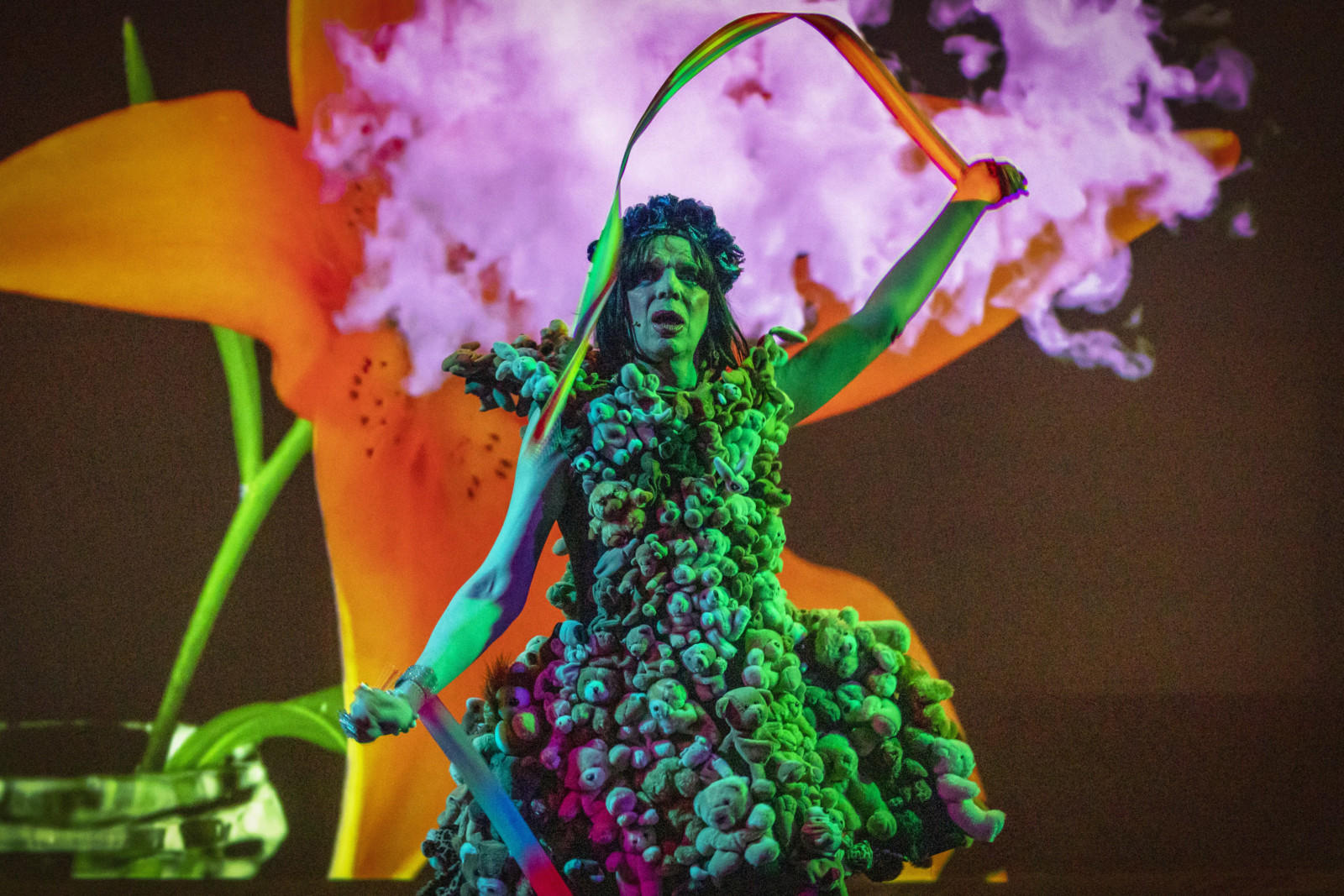 David Hoyle wearing a dress made of teddy bears, with pink smoke in the background.