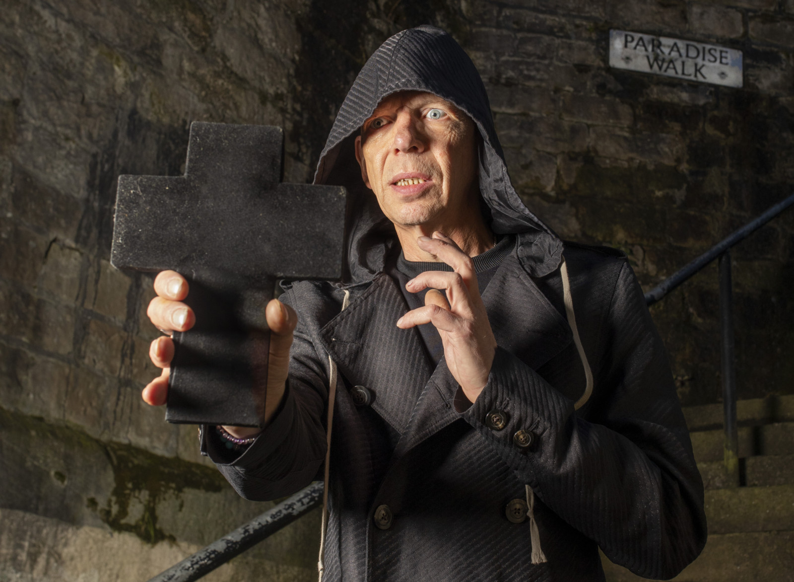 David Hoyle holding a crucifix in front of him and looking fearful