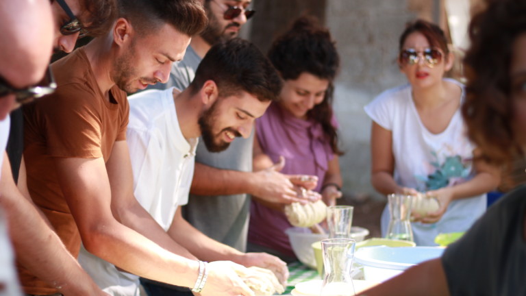 A group of people kneading dough outside in the sun
