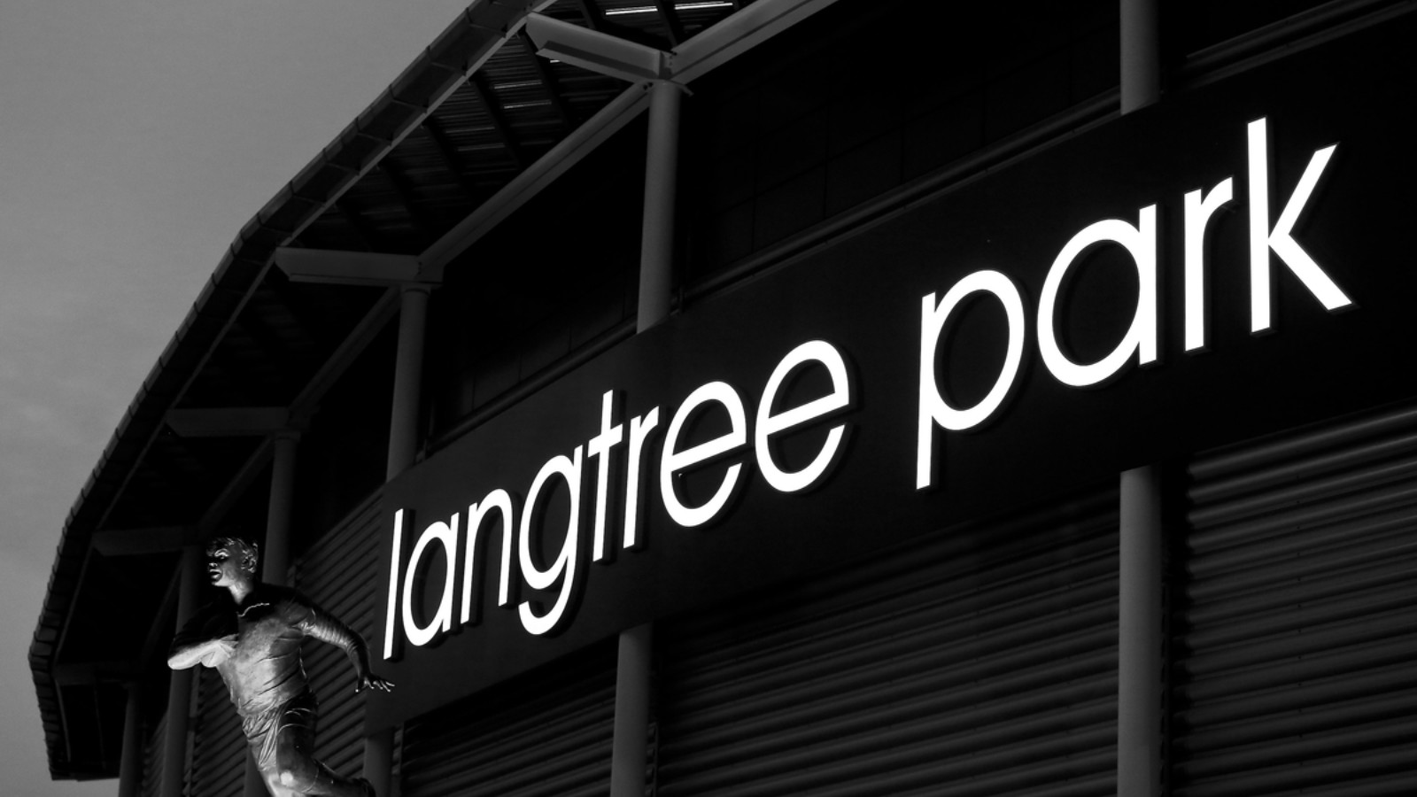 A black and white image of the front of a stadium. The sign reads 'langtree park'.