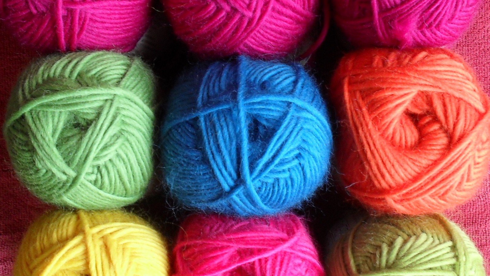 9 brightly coloured balls of wool are arranged in a square.