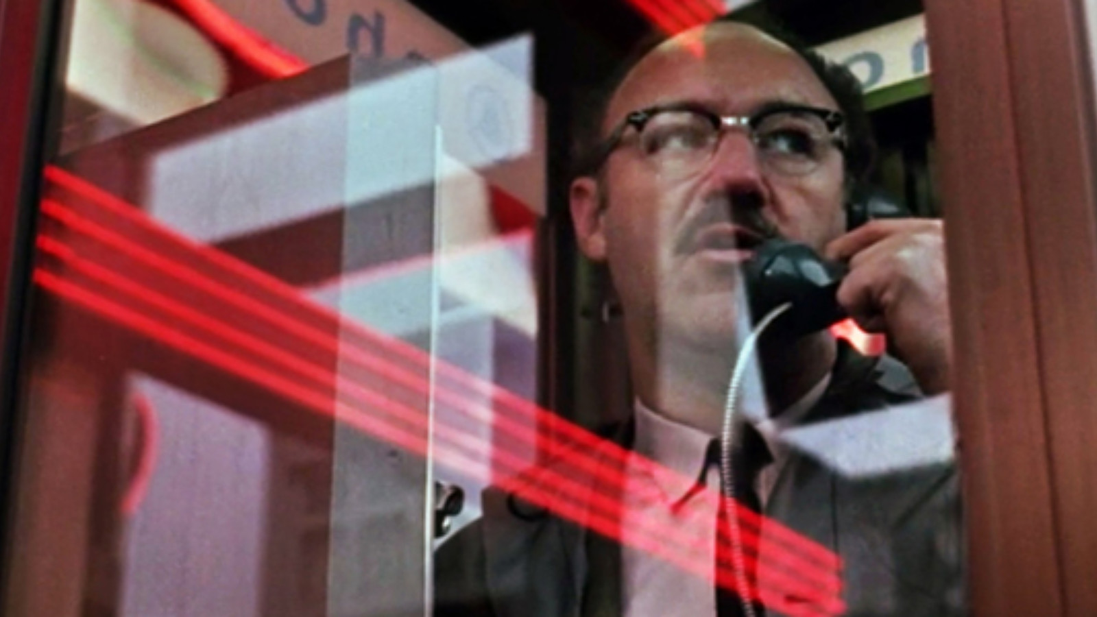 A still from the film The Conversation of a man in a phone box speaking down a phone.