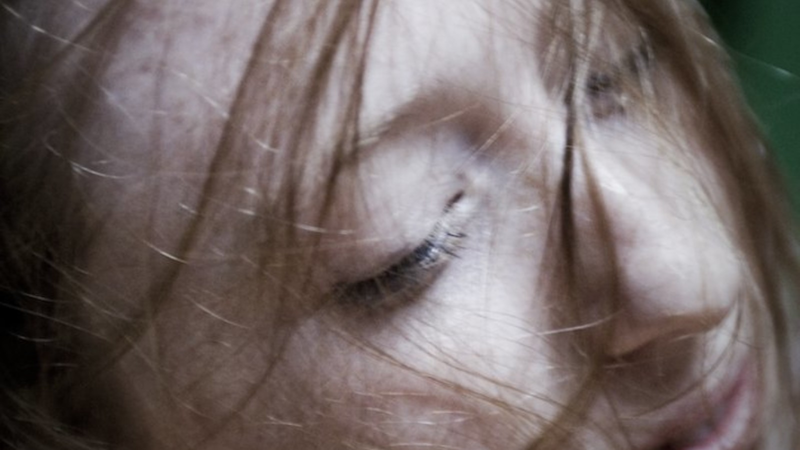 A close up image of a women's face with her hair faintly covering her face.