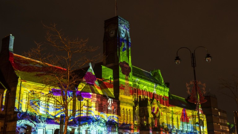 St Helens Town Hall is lit up with a huge multicoloured projection against a night sky.